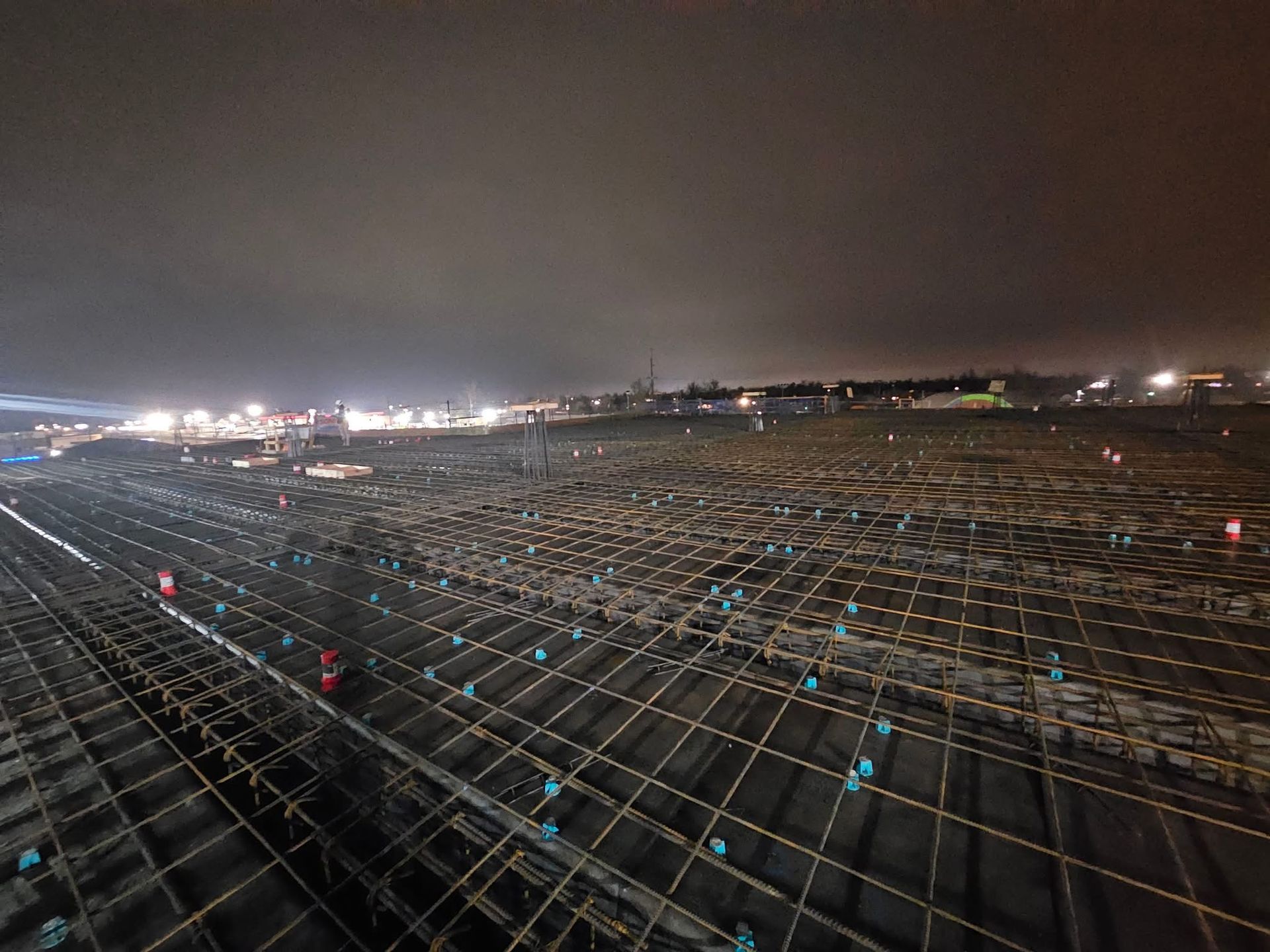 Nighttime view of reinforced steel rebar grid prepared for concrete pouring on a large commercial project.