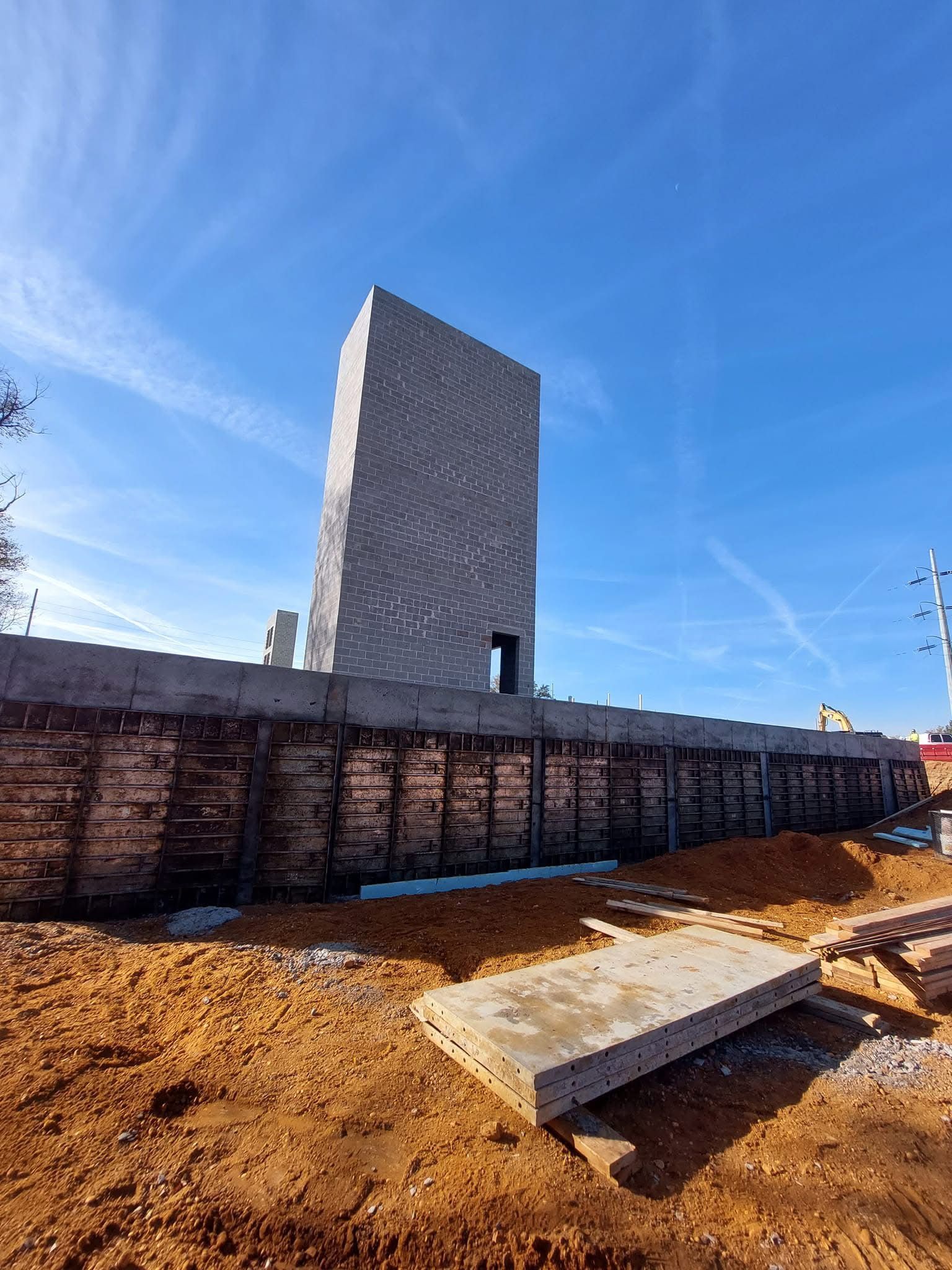 Concrete or brick structure under a clear blue sky at a construction site.