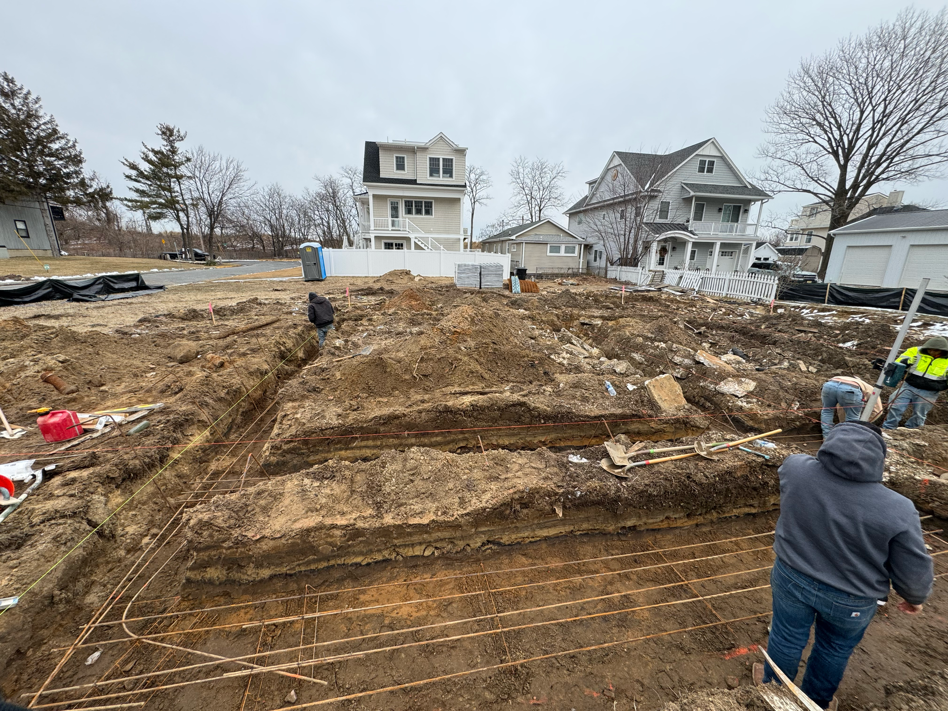 Construction crew preparing a residential site with excavation and grading for new building foundations.
