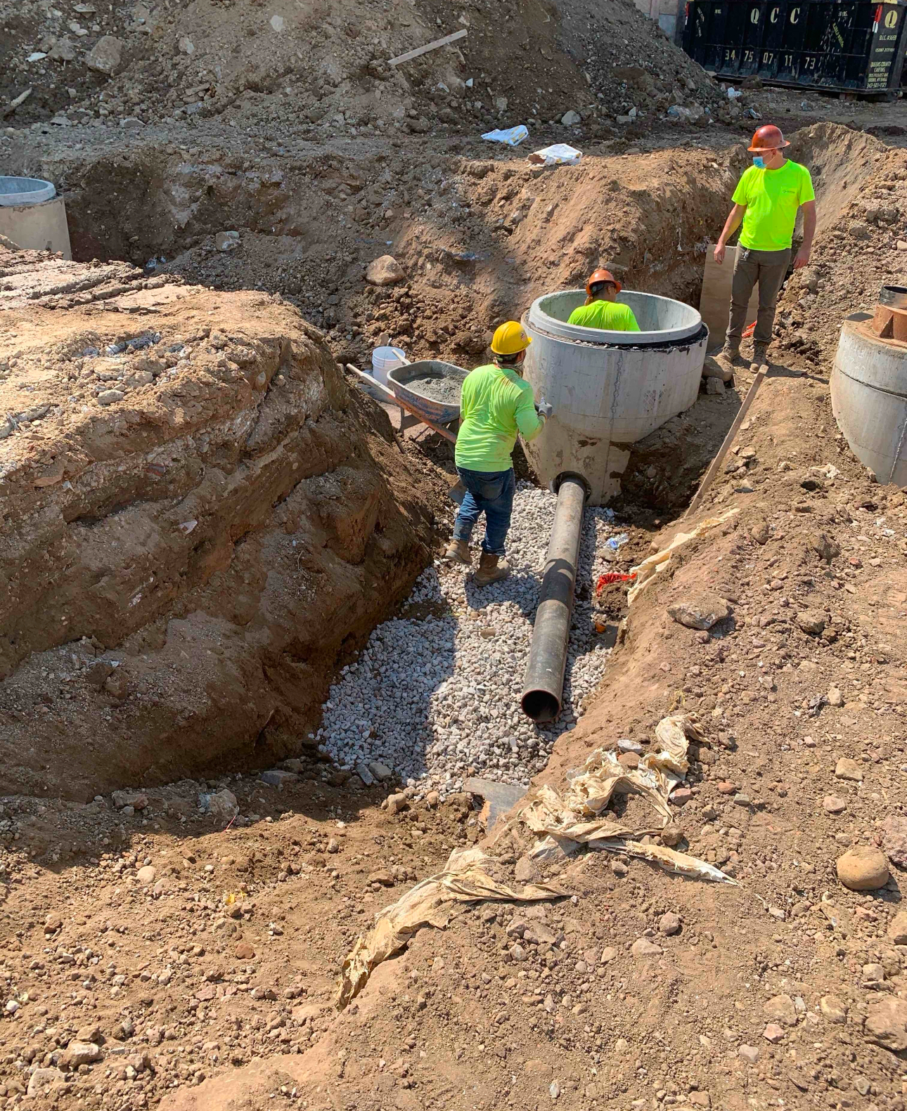 Construction crew installing a precast concrete manhole as part of underground utility infrastructure.