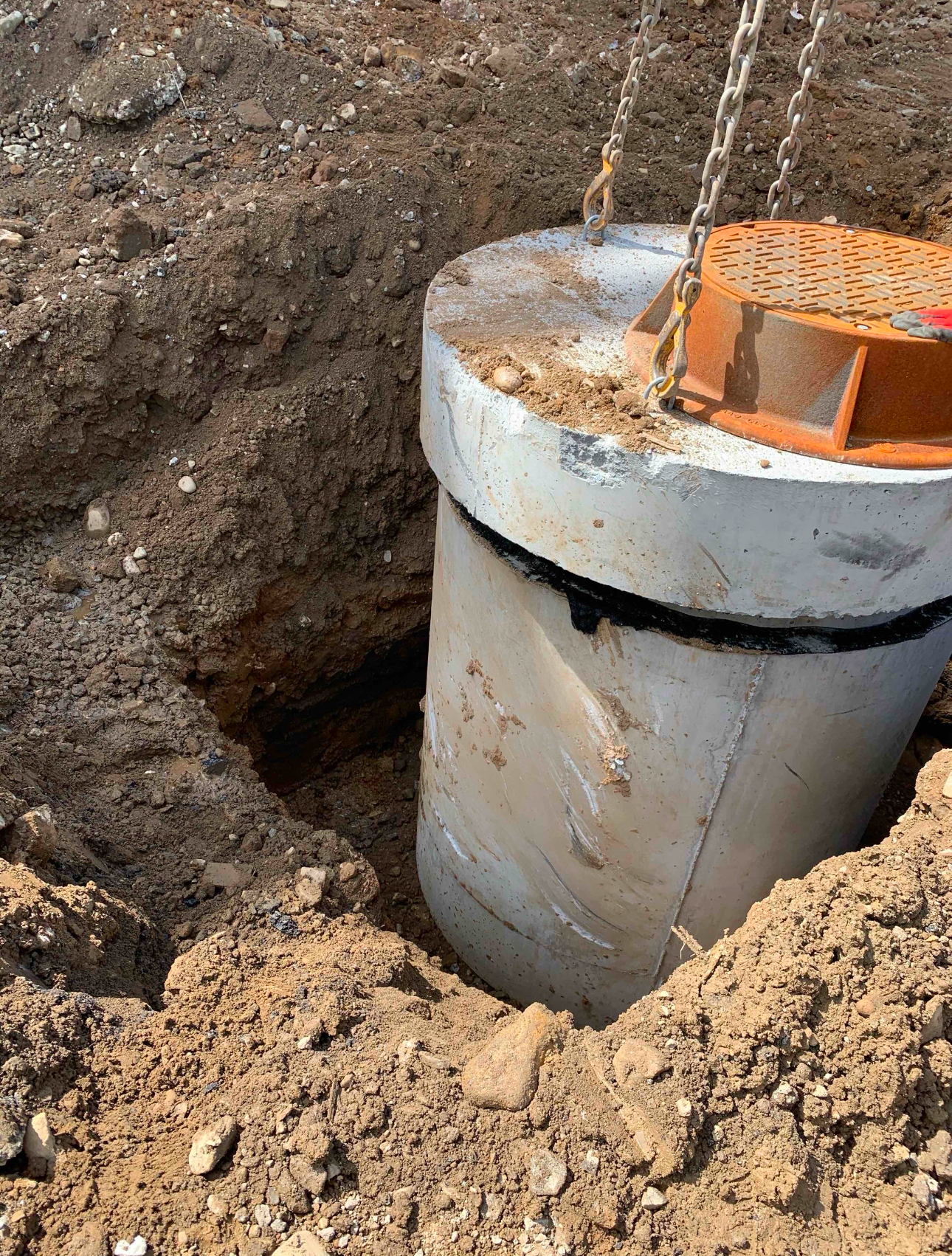 Precast concrete manhole structure being installed for stormwater or sewer infrastructure.