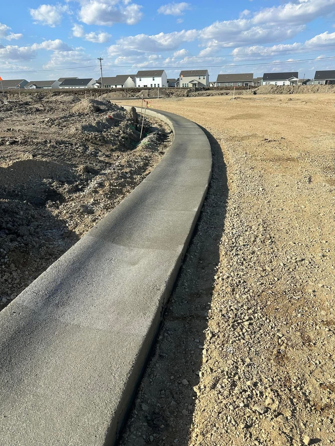 Freshly paved roadway connecting a new residential development under construction.