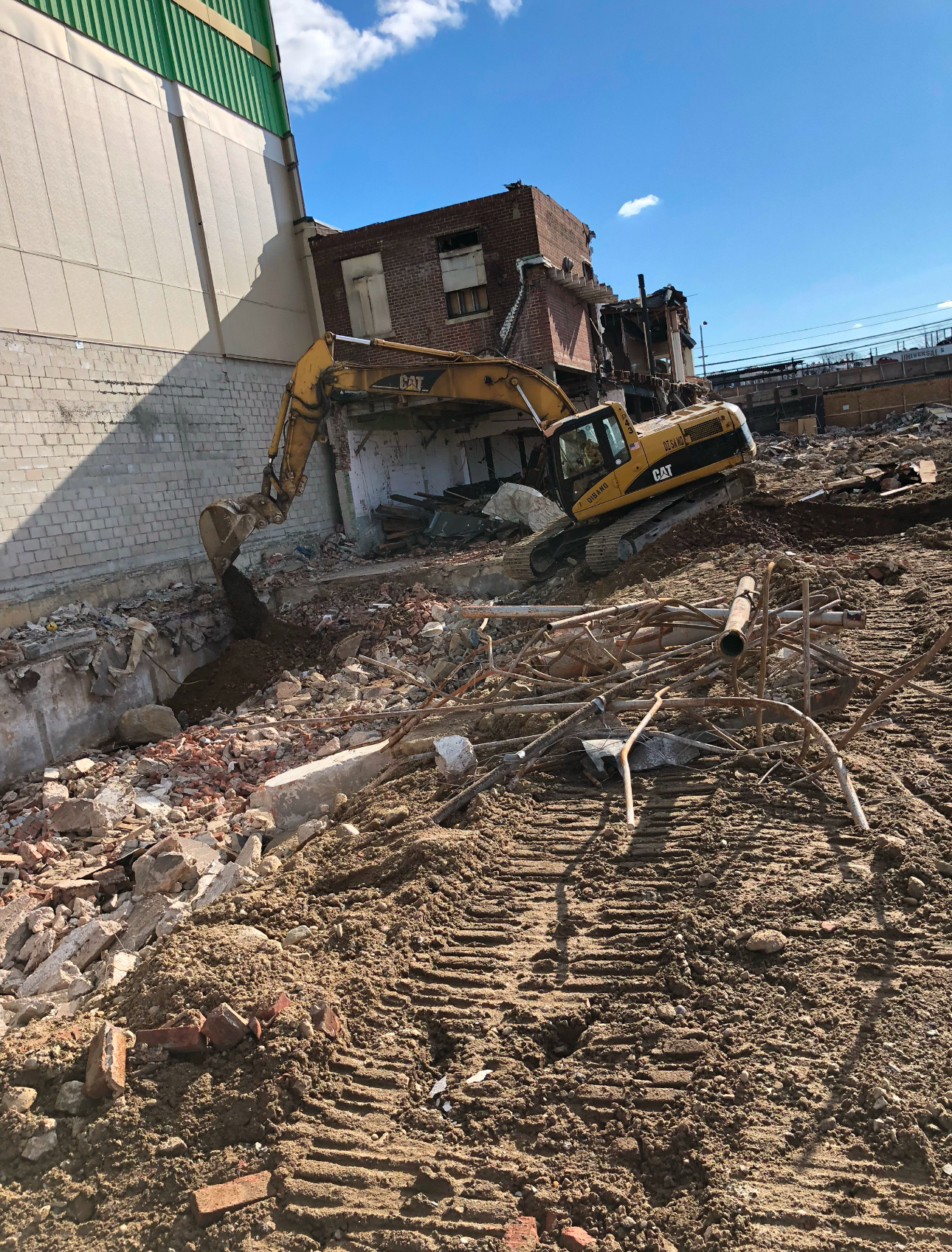 Excavator demolishing an old building during site preparation for new construction.