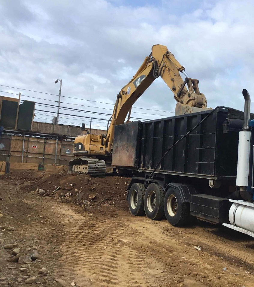 Heavy equipment excavating and loading soil into a dump truck during a site development project.