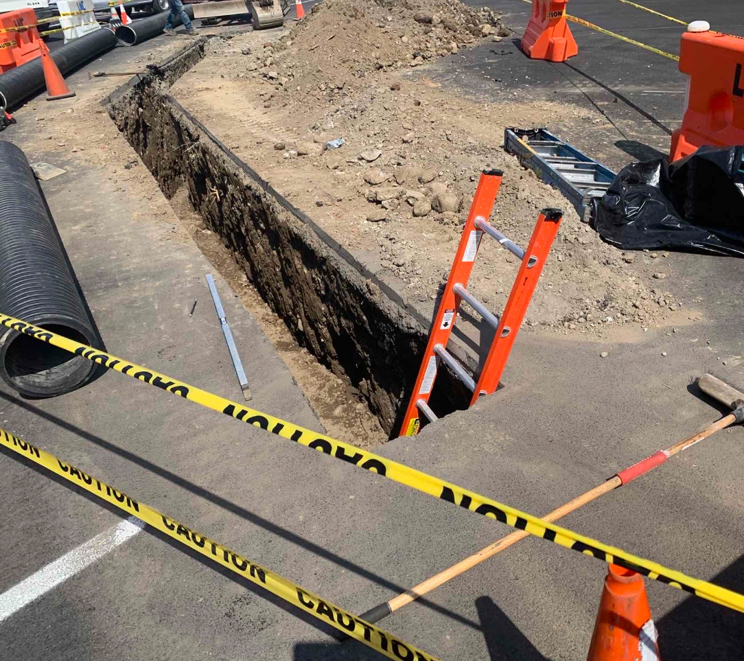 Excavated trench along a roadway prepared for underground utility or conduit installation.