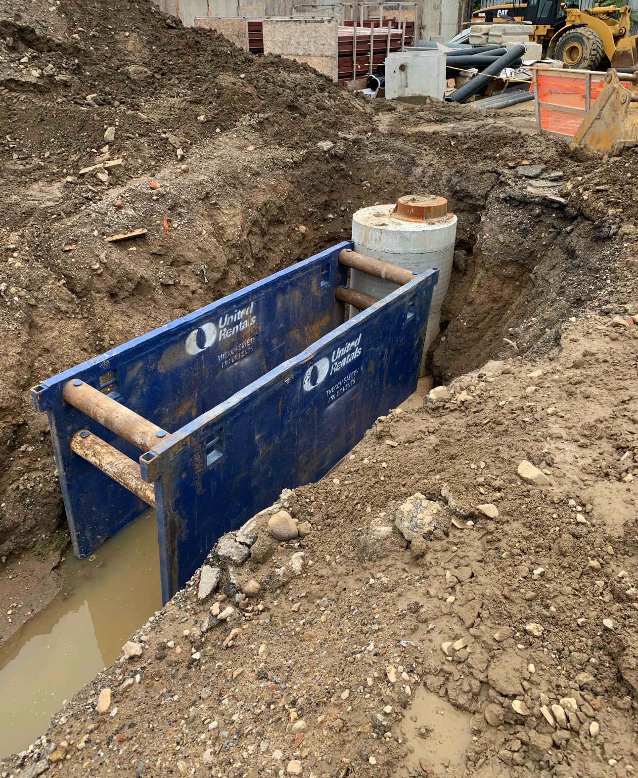 Open excavation site with underground utility access point installation in progress.