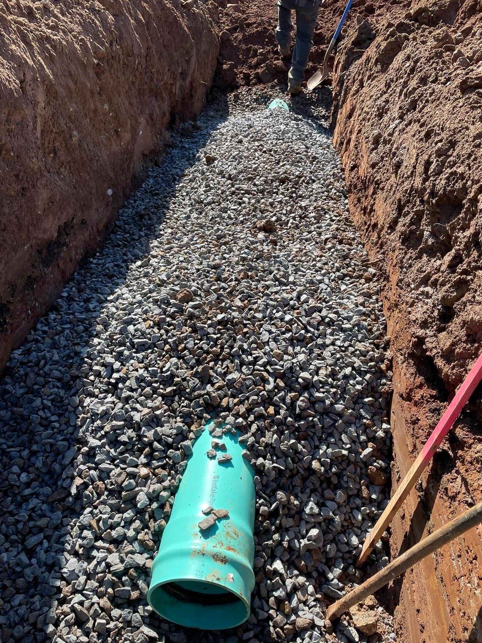 Gravel bed prepared inside a deep trench for drainage or underground utility infrastructure.
