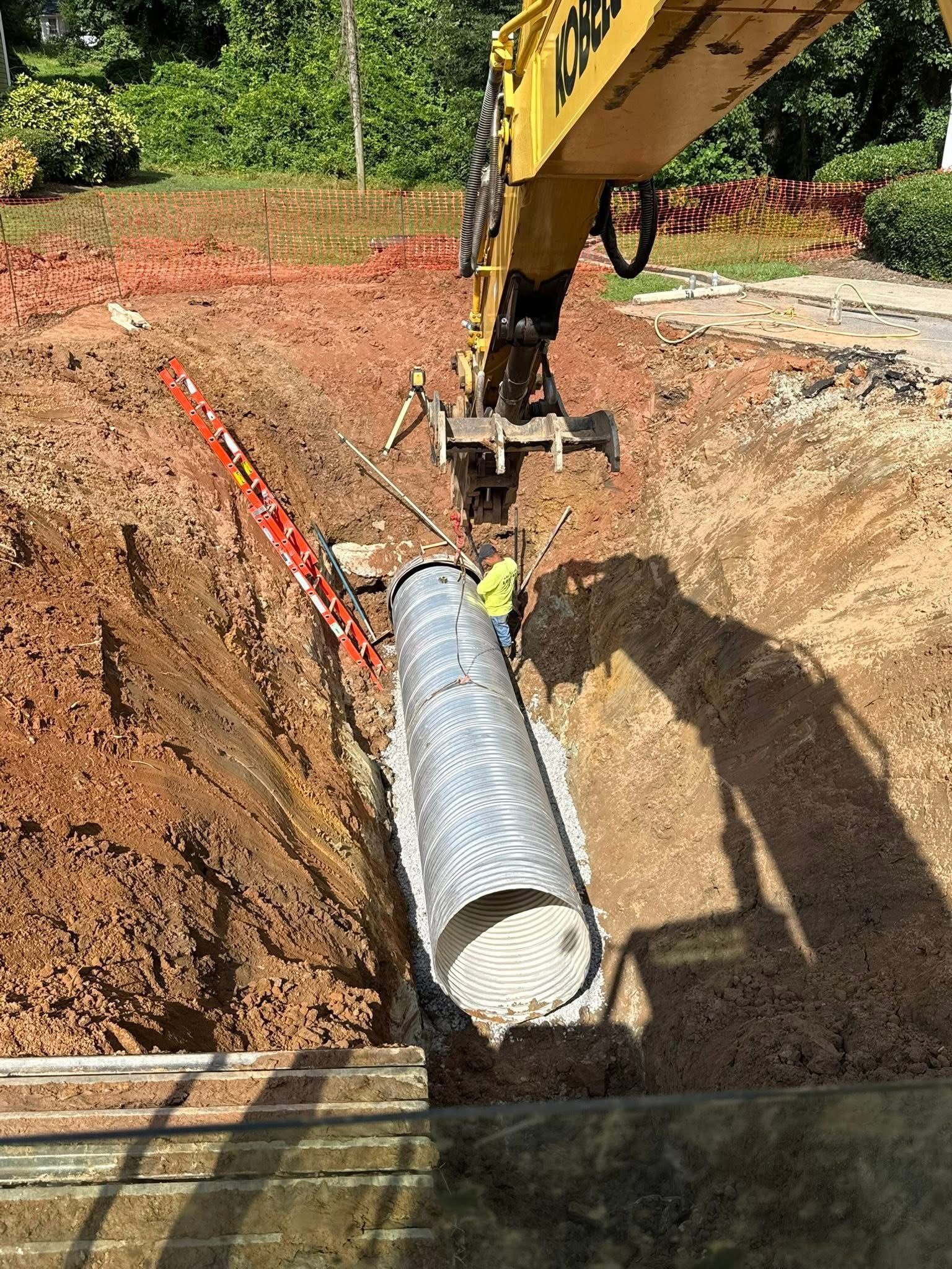 Excavator digging a deep trench for utility line installation at a residential development site.