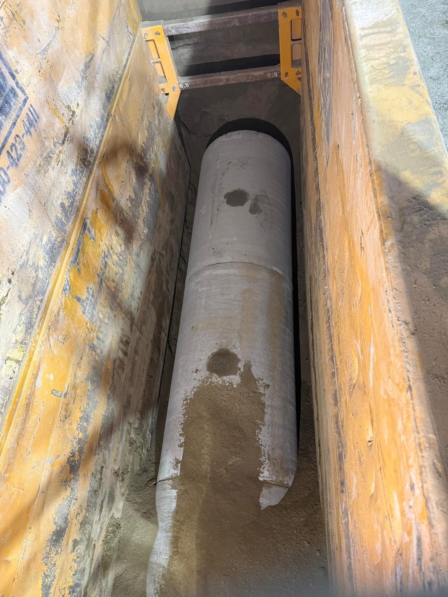 Concrete pipe installed in a reinforced underground vault for drainage or utility infrastructure.