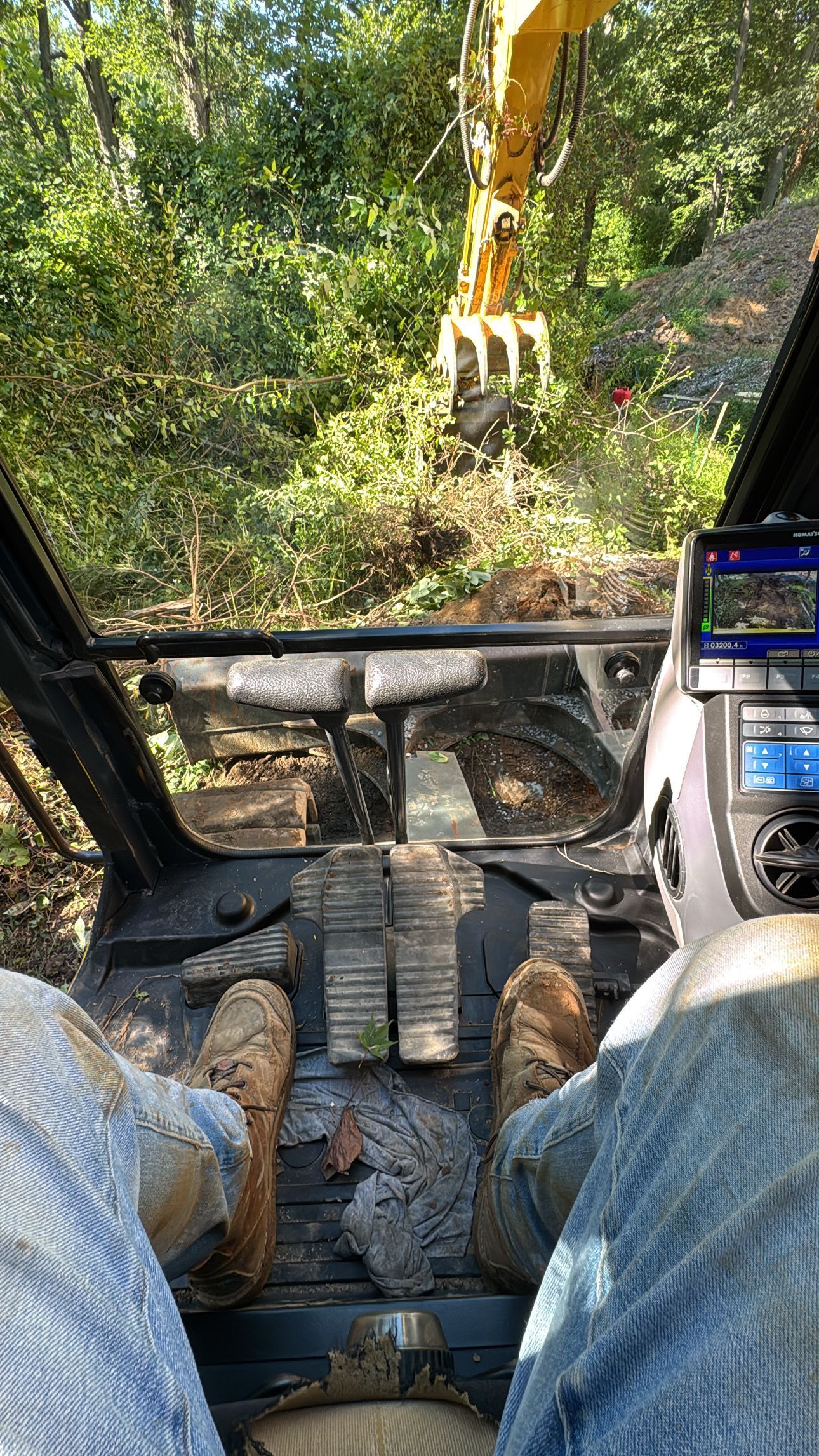 Excavator removing trees and clearing land to prepare the site for construction and utility installation.