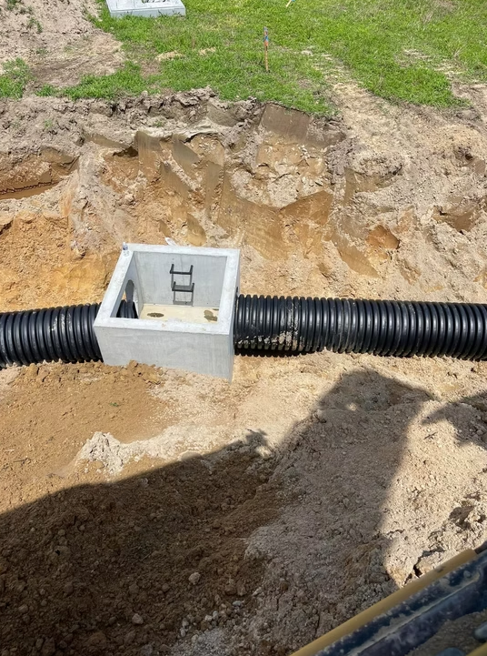 Excavated site with a newly installed concrete utility vault for drainage or electrical systems.