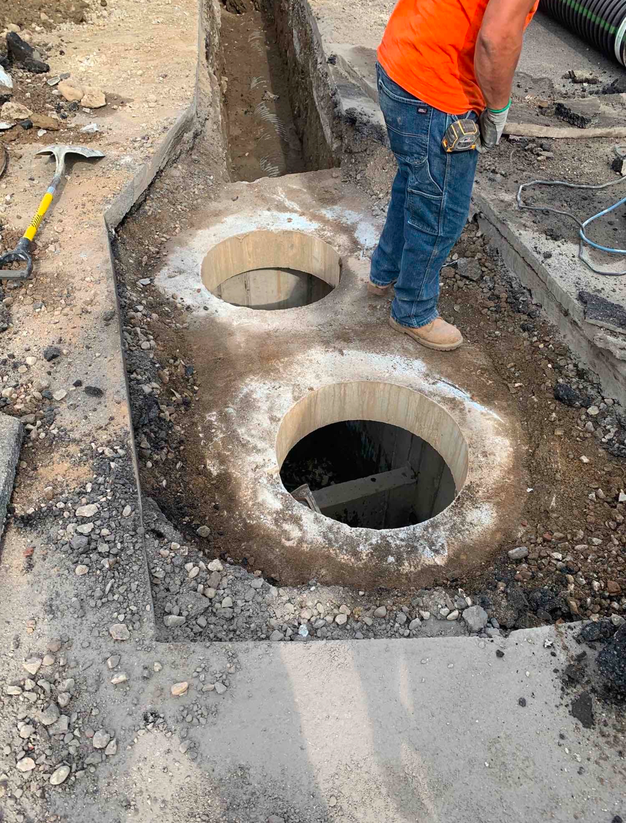 Construction worker preparing an underground access point for utility or drainage system installation.