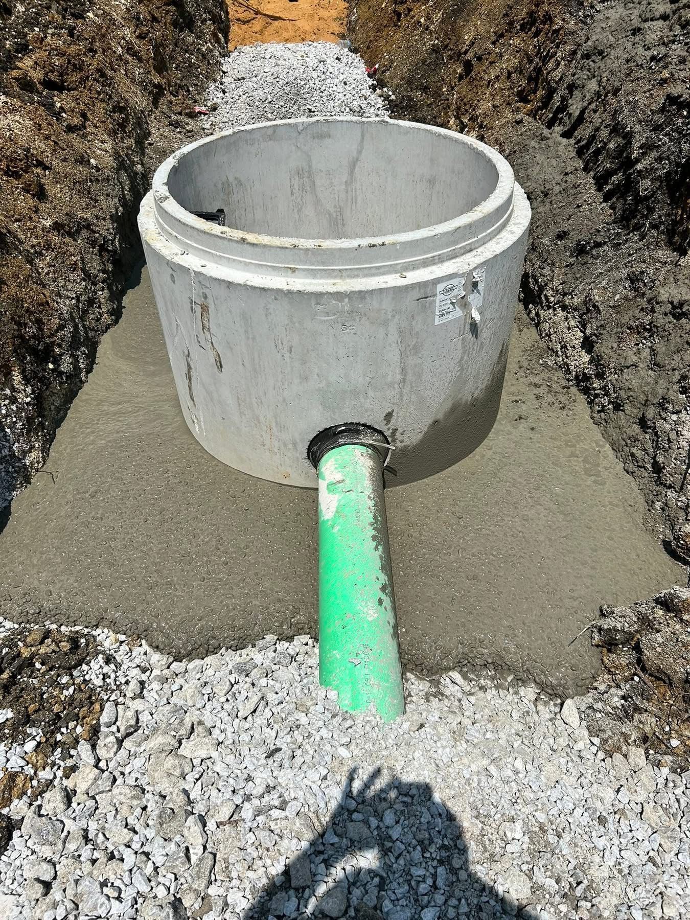Concrete manhole base positioned in a prepared trench for underground drainage or utility system.
