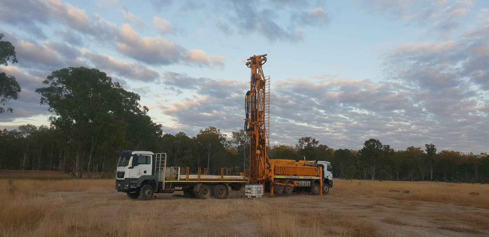 Drilling Rig Trucks Situated in a Field — Grid Drilling in Childers, QLD