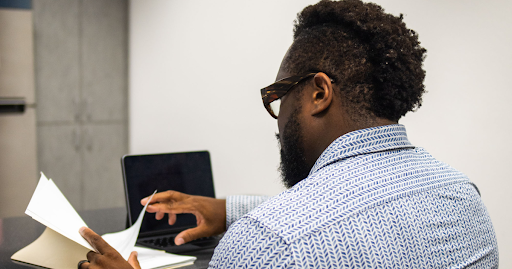 Professional man reviewing documents at a laptop during a concierge primary care consultation, repre