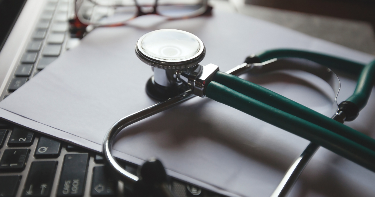 Stethoscope resting on a laptop and paperwork, symbolizing executive concierge medicine that protect