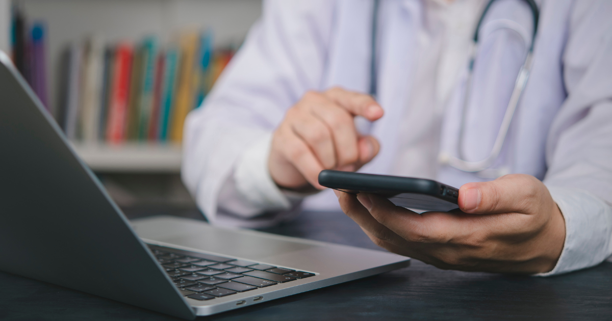 Physician using a smartphone and laptop during mobile concierge care, representing modern mobile doc