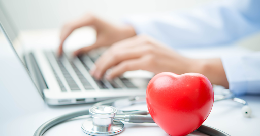 Stethoscope and heart model near a laptop, symbolizing personalized health plans and concierge healt