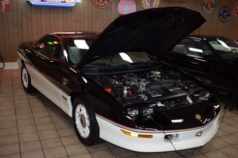 A black and white car with the hood up in a garage