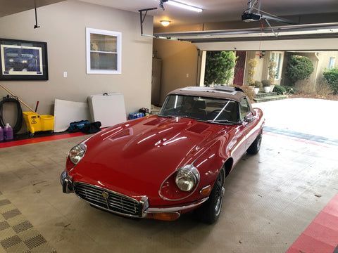 A red sports car is parked in a garage.
