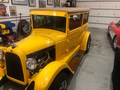 A yellow car is parked in a garage next to other cars.
