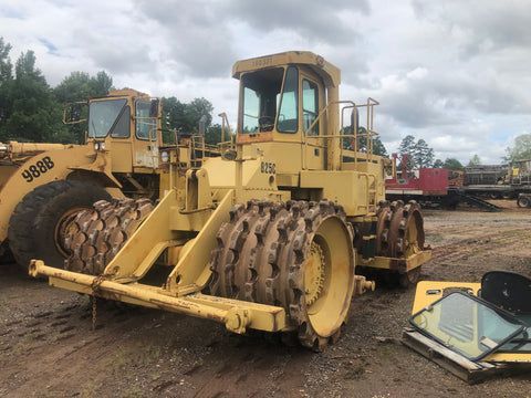 A yellow bulldozer is parked in a dirt lot next to a tractor.