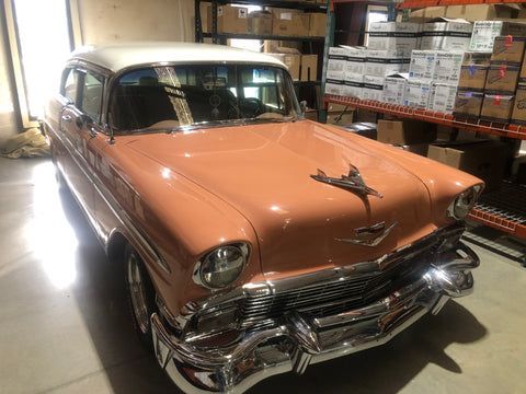 An old car is parked in a garage next to boxes.