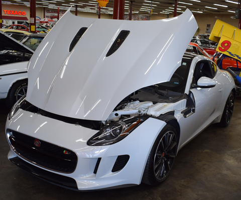 A white sports car with the hood up in a garage