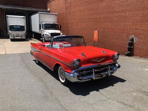 A red convertible car is parked in front of a brick building.