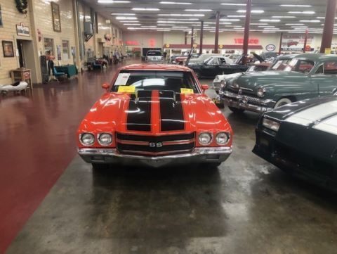 A red car with black stripes is parked in a garage.