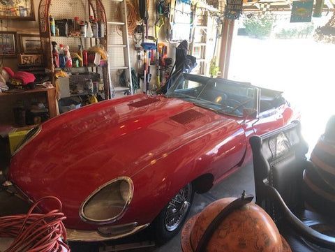 A red sports car is parked in a garage next to a globe.
