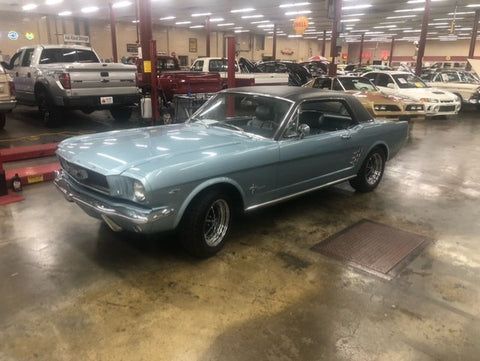 A blue mustang convertible is parked in a garage.