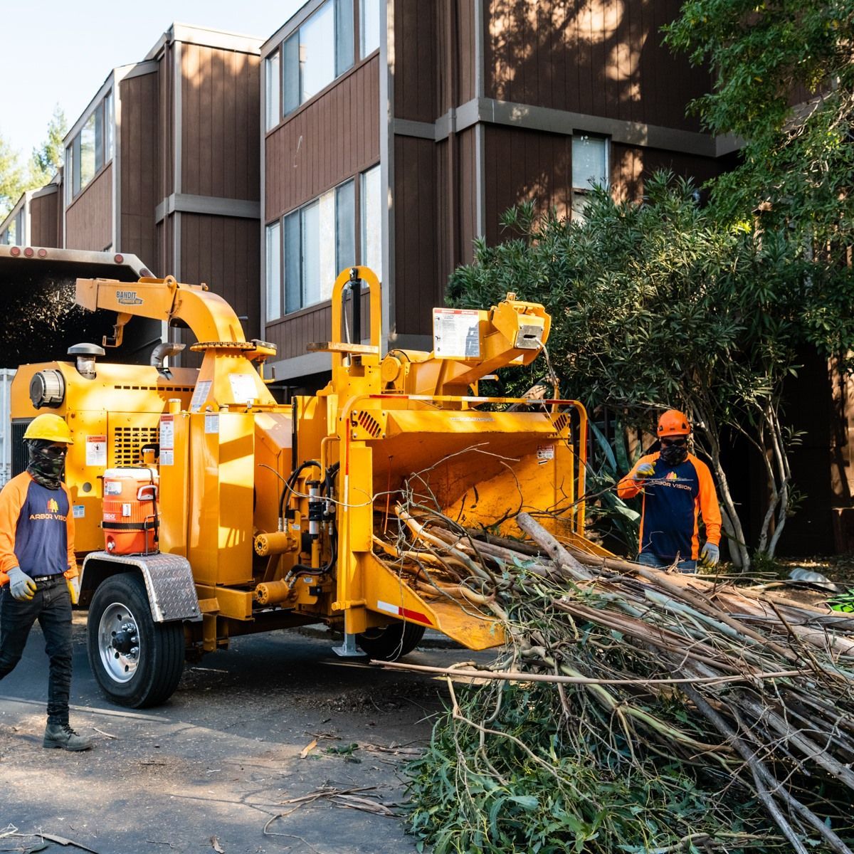 A man is standing next to a tree chipper in front of a building