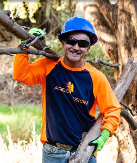 Arbor Vision team member smiling while carrying branches