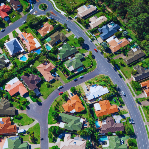 Aerial view of a suburban neighborhood with tree-lined streets and green spaces.