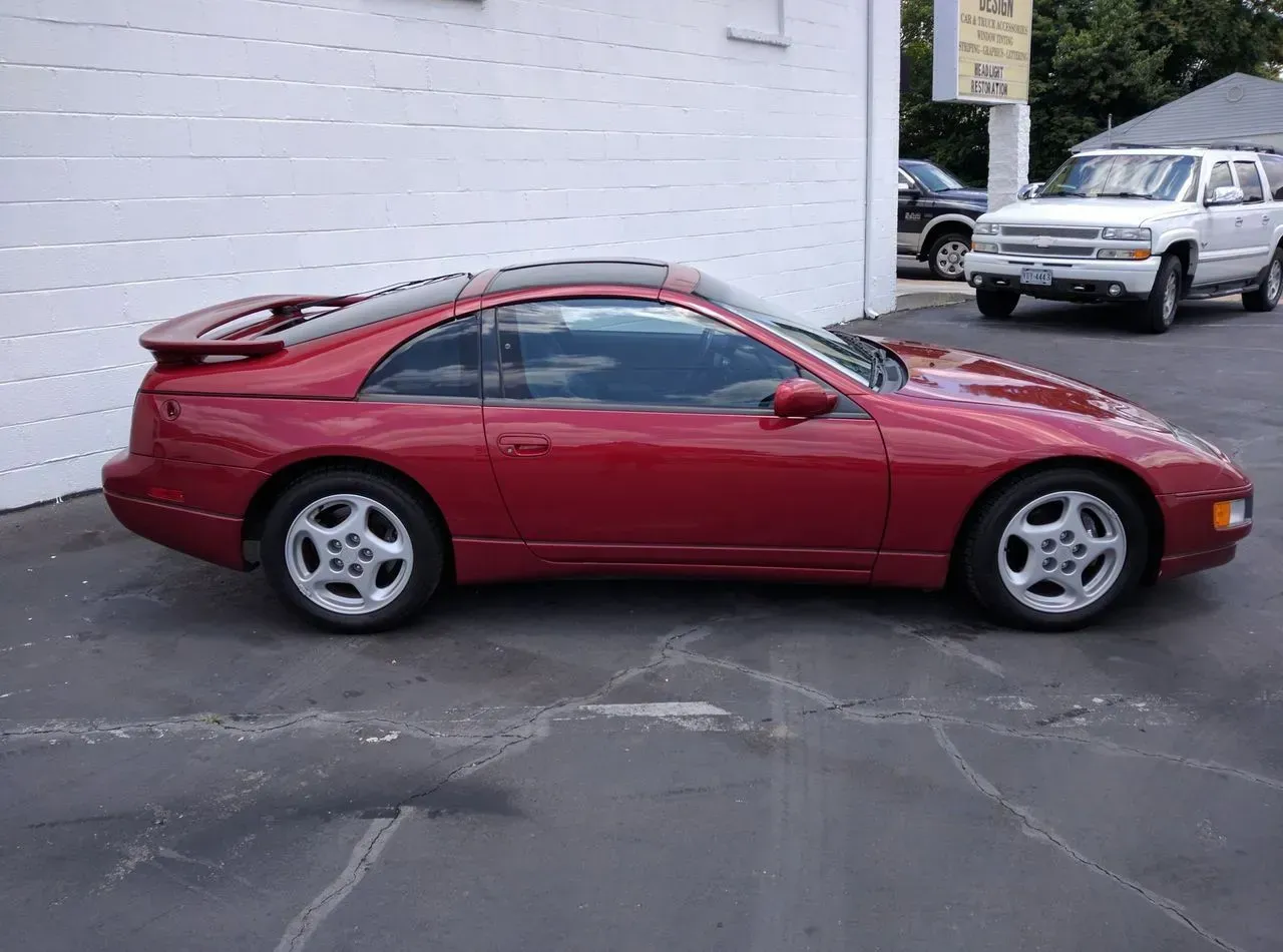 A red sports car is parked in front of a white garage door.