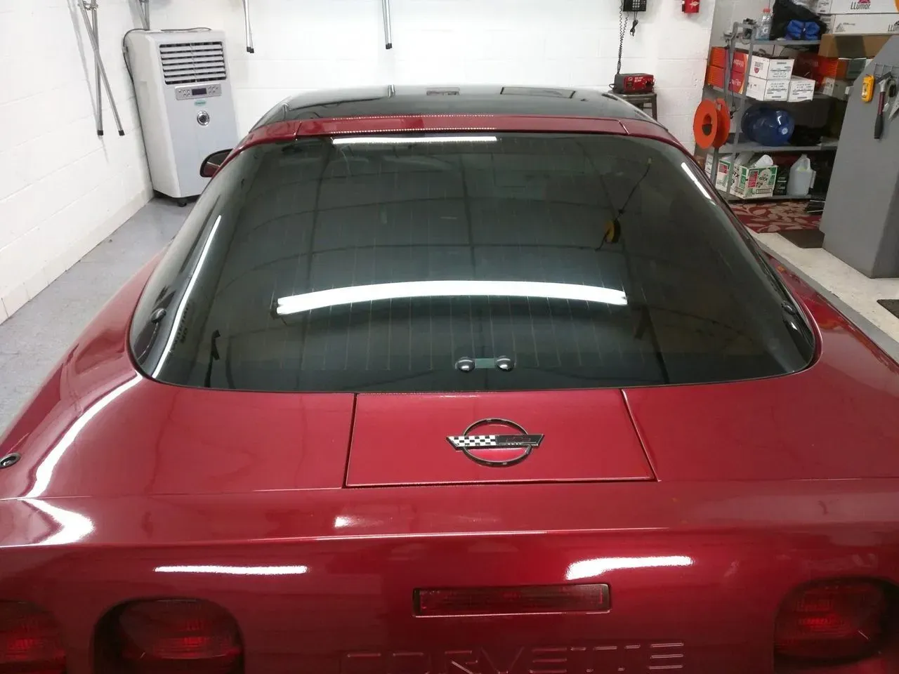 A red nissan car is parked in a garage.
