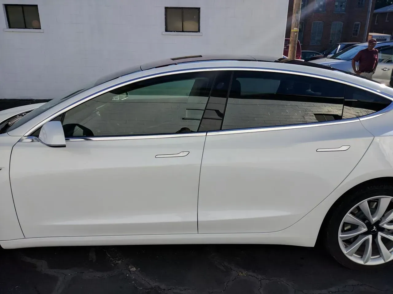 A white tesla model 3 is parked in a parking lot.