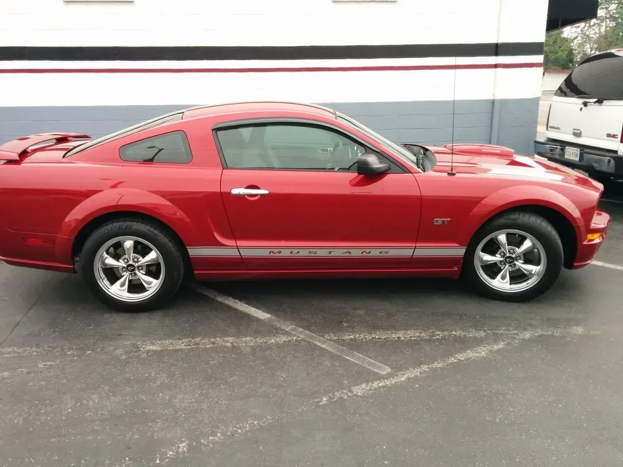 A red mustang is parked in a parking lot.
