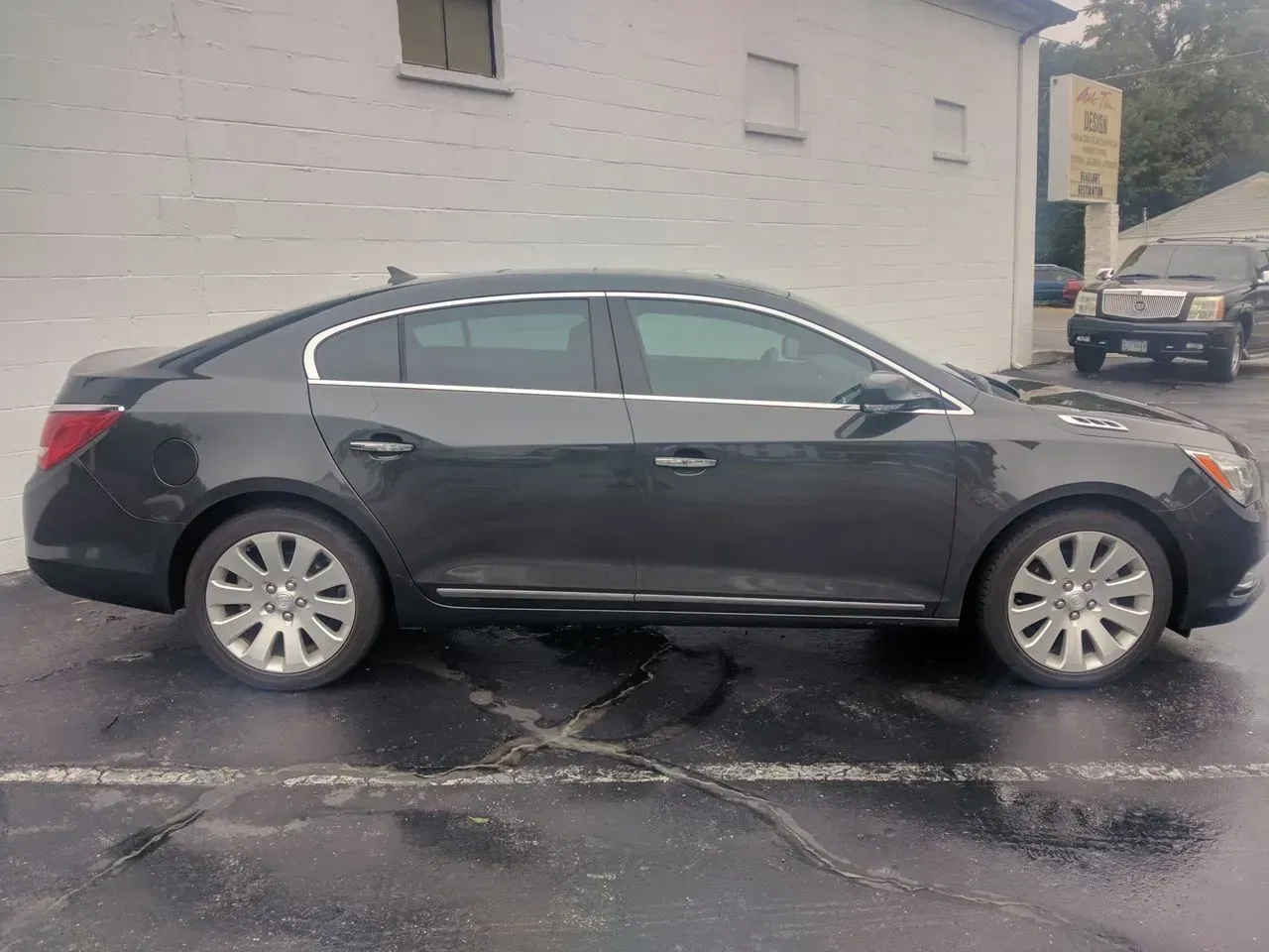 A black car is parked in front of a white building.