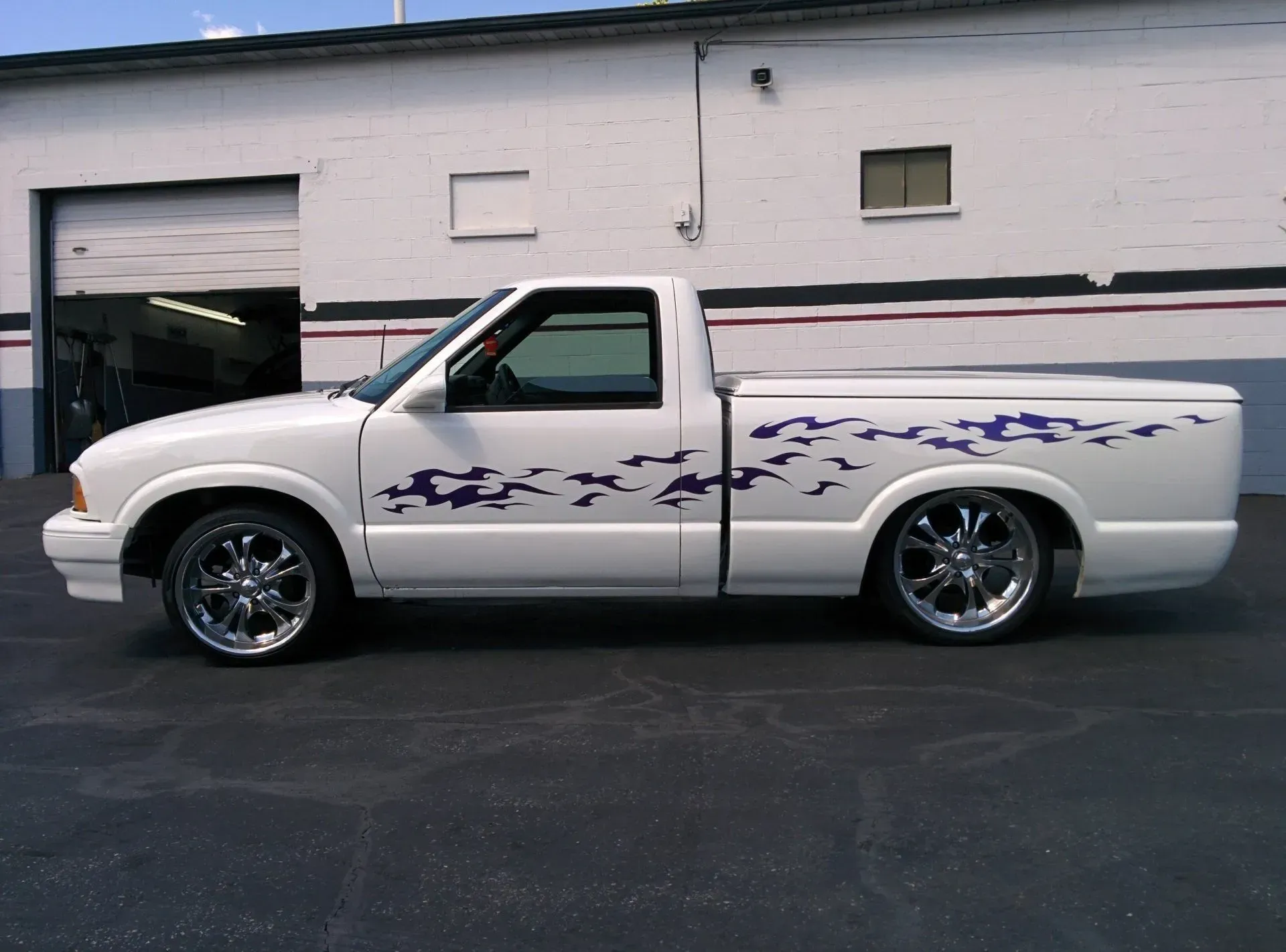 A white truck with birds on the side is parked in front of a building.
