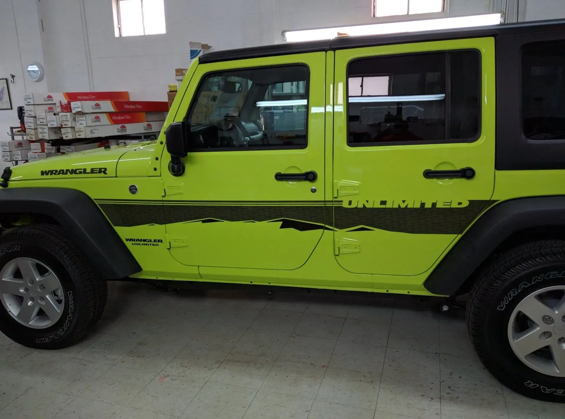 A yellow jeep wrangler is parked in a garage.