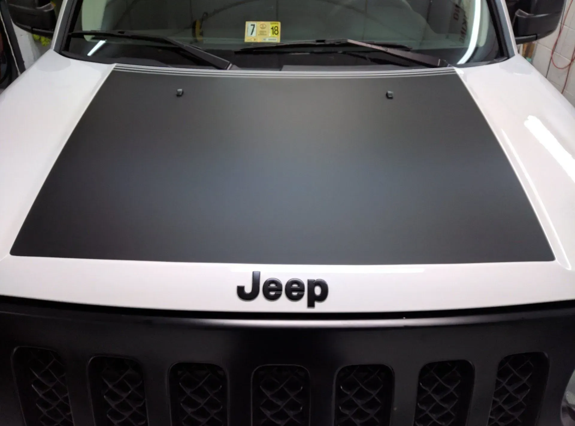 A white jeep with a black hood and grille.