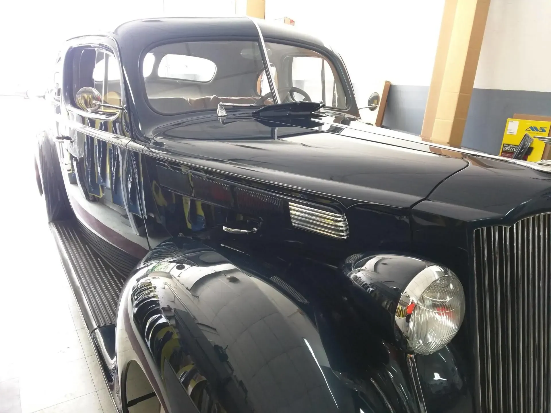 An old black car is parked in a garage.