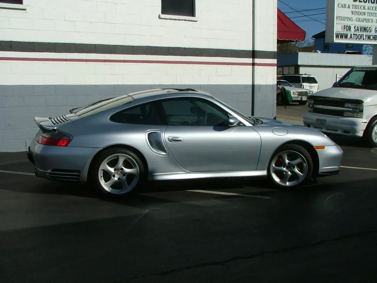 A silver sports car is parked in front of a building.