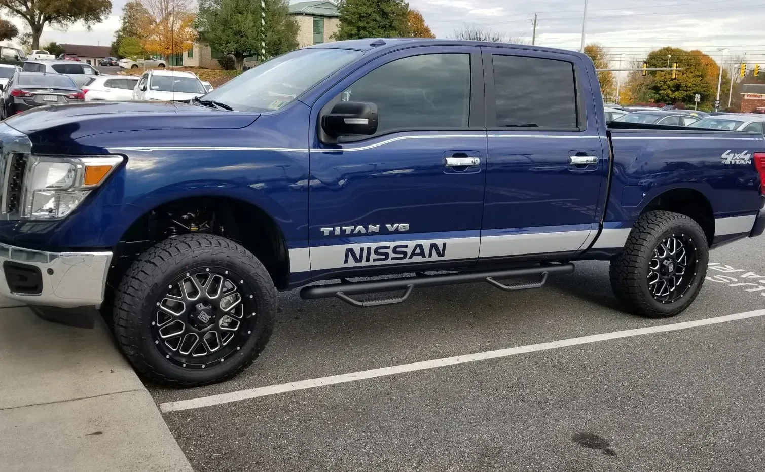 A blue nissan titan truck is parked in a parking lot.