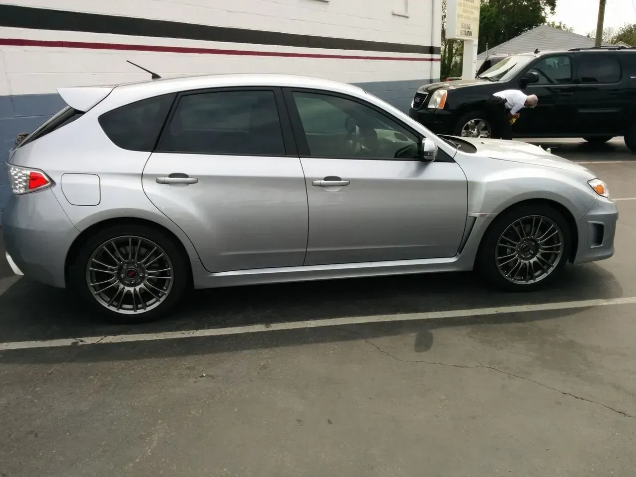 A silver subaru is parked in a parking lot.