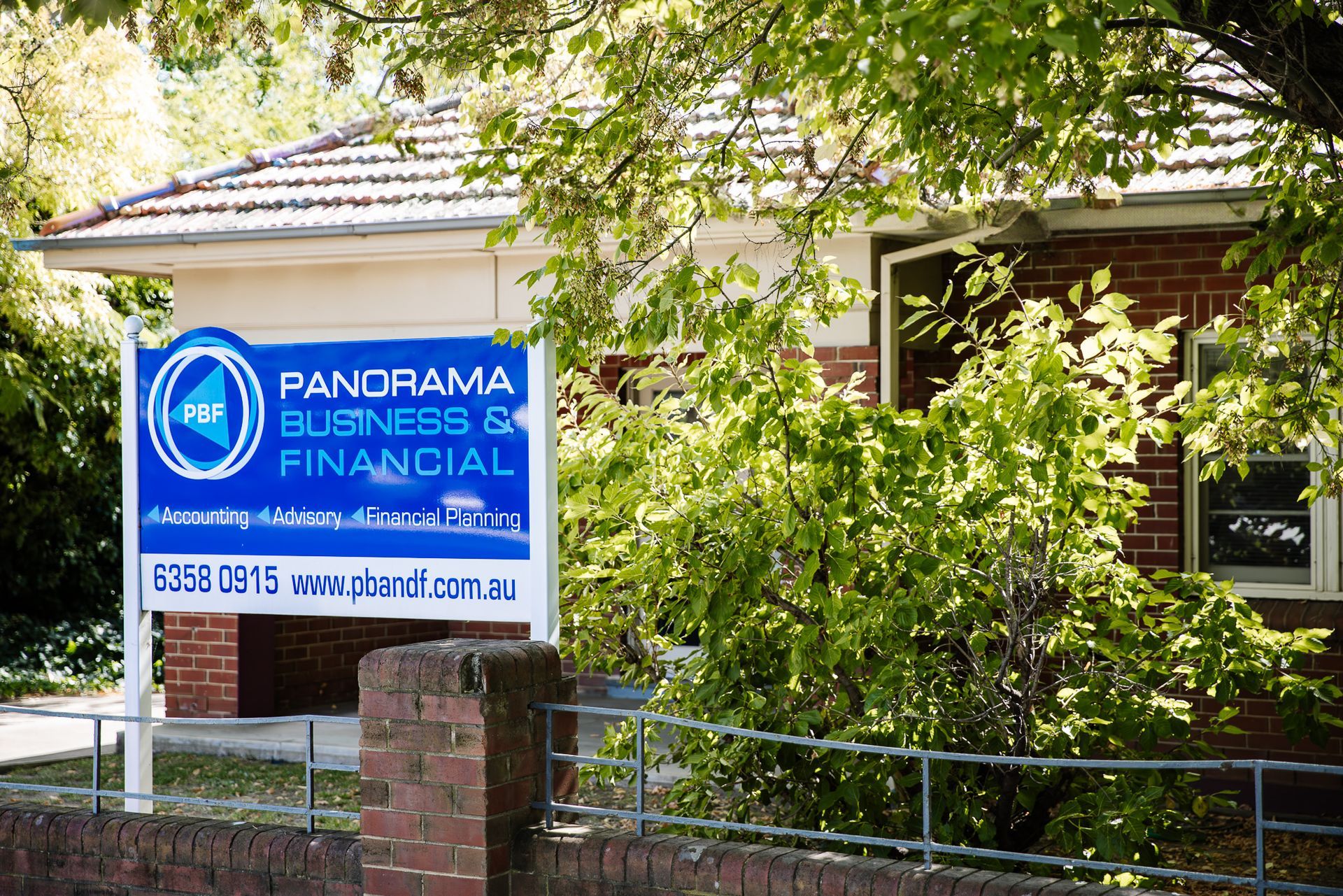 Panorama Business Financial sign in front of a house, surrounded by greenery