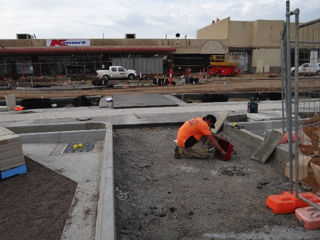 A Man is Kneeling down in front of a Building with a k-mart sign on it — Mawson Constructions in Kialla, VIC