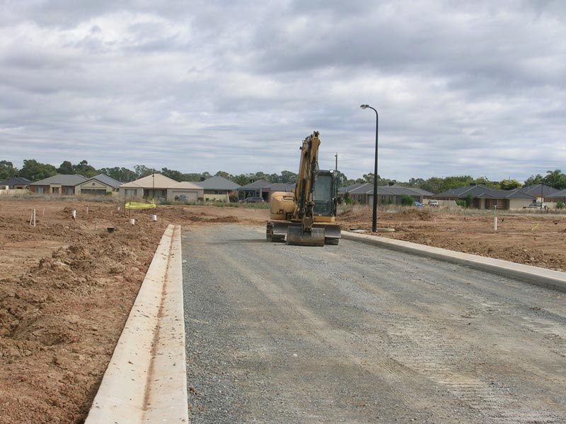 Construction Vehicle is Driving Down Concrete Road — Mawson Constructions in Kialla, VIC